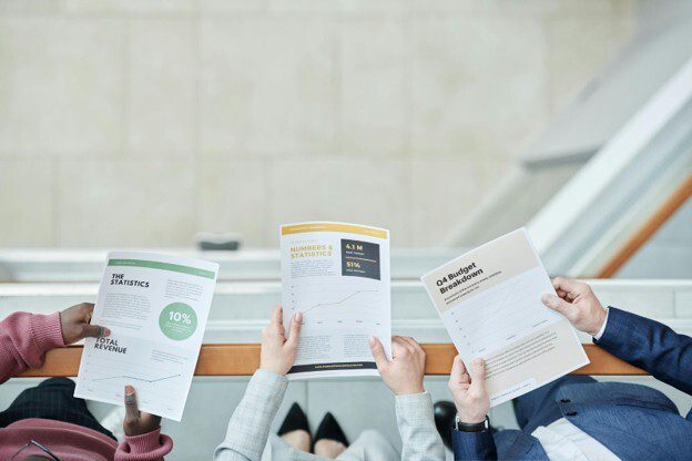 Modern finance team reviewing printed finance metrics